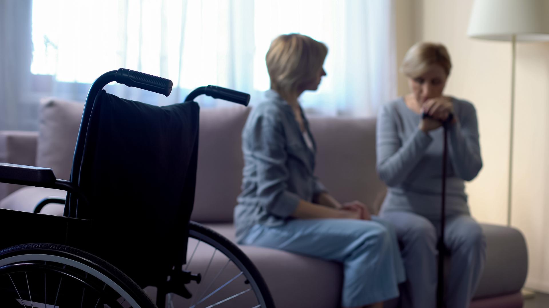 Nurse talking with depressed disabled senior woman in rehabilitation center